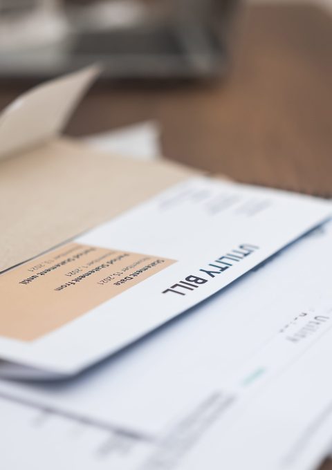 Utility bill statement details, displaying due amount, alongside a phone calculator, set on a wooden apartment table. Financial responsibility in focus.